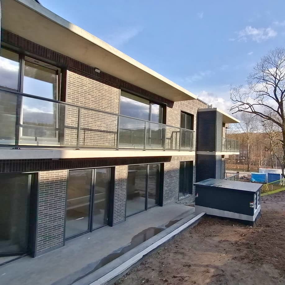 Namas su dideliu balkonu ir kiemu, pabrėžiantis neseniai užbaigtus langų montavimo darbus.