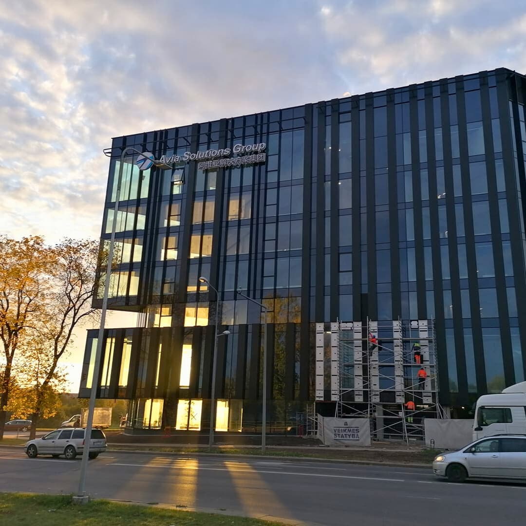 Didelis pastatas su daugybe langų, demonstruojantis pagrindinės statybos įmonės fasado montavimą.